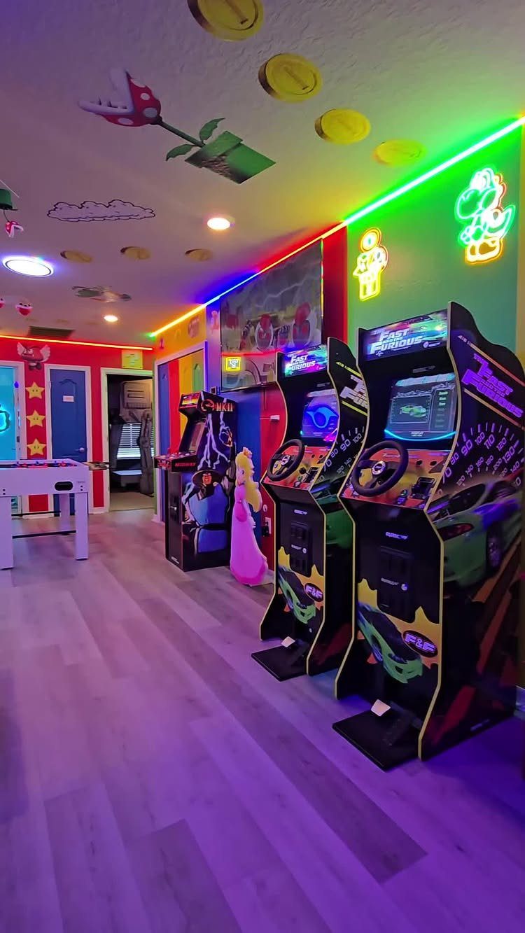 Arcade game room with racing cabinets, neon lights, and Mario themed decorations.