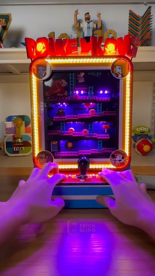 LEGO Donkey Kong arcade machine with glowing lights being played by two hands.