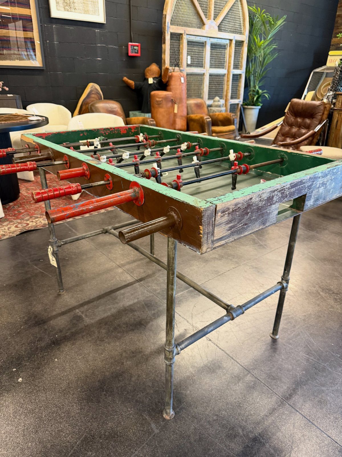 Vintage foosball table with green surface and red handles in a furnished room.