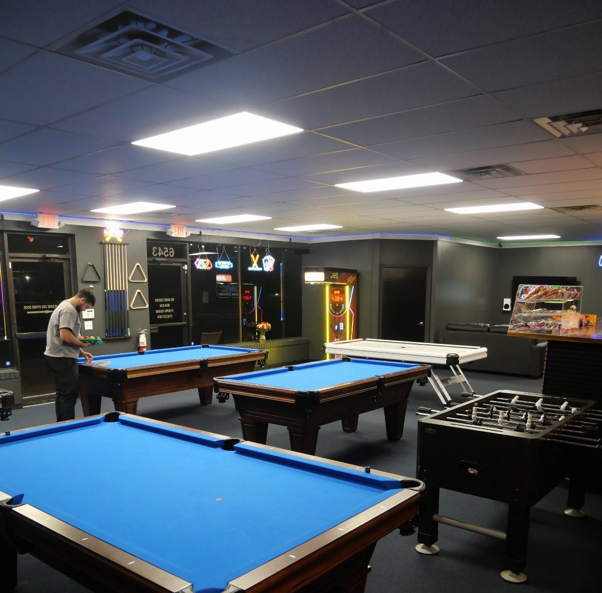 Game room with blue pool tables, foosball, air hockey, and arcade machines.