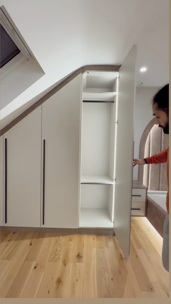 White built-in wardrobe under a sloped ceiling in a modern loft conversion room.