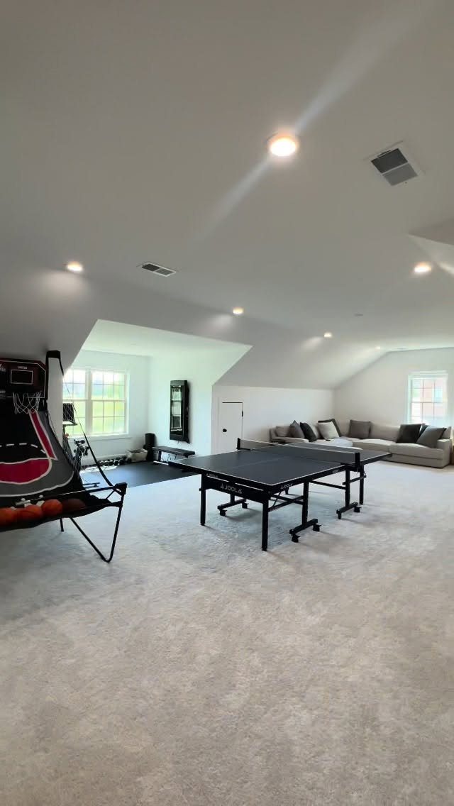 Finished attic game room with ping pong table, basketball hoop, and sectional sofa.