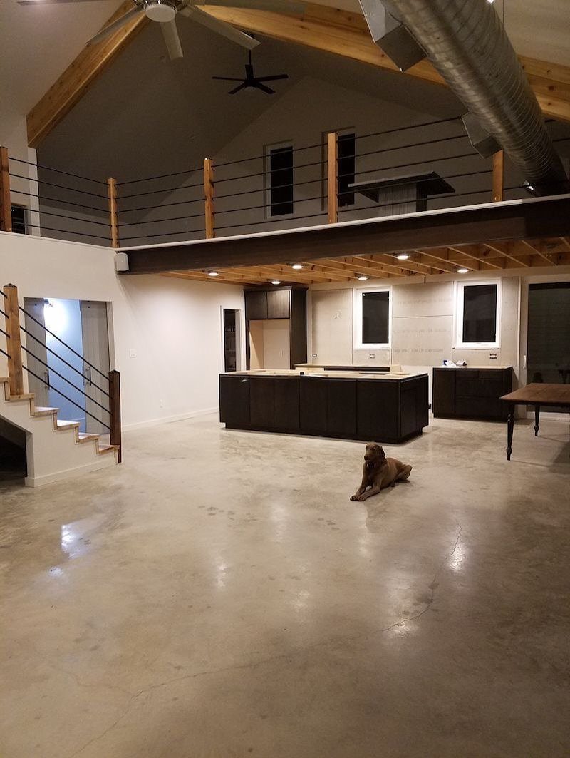 Open interior with polished concrete floors, exposed beams, and an industrial loft area.