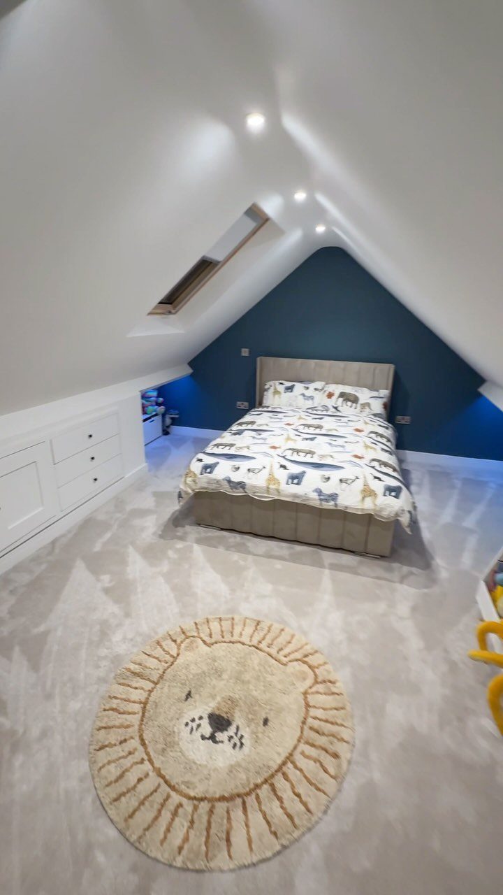 Converted attic bedroom with sloped ceilings, skylight, blue wall, and lion rug.