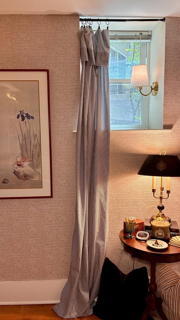 Cozy room corner with a table lamp, wall sconce, and striped curtains.