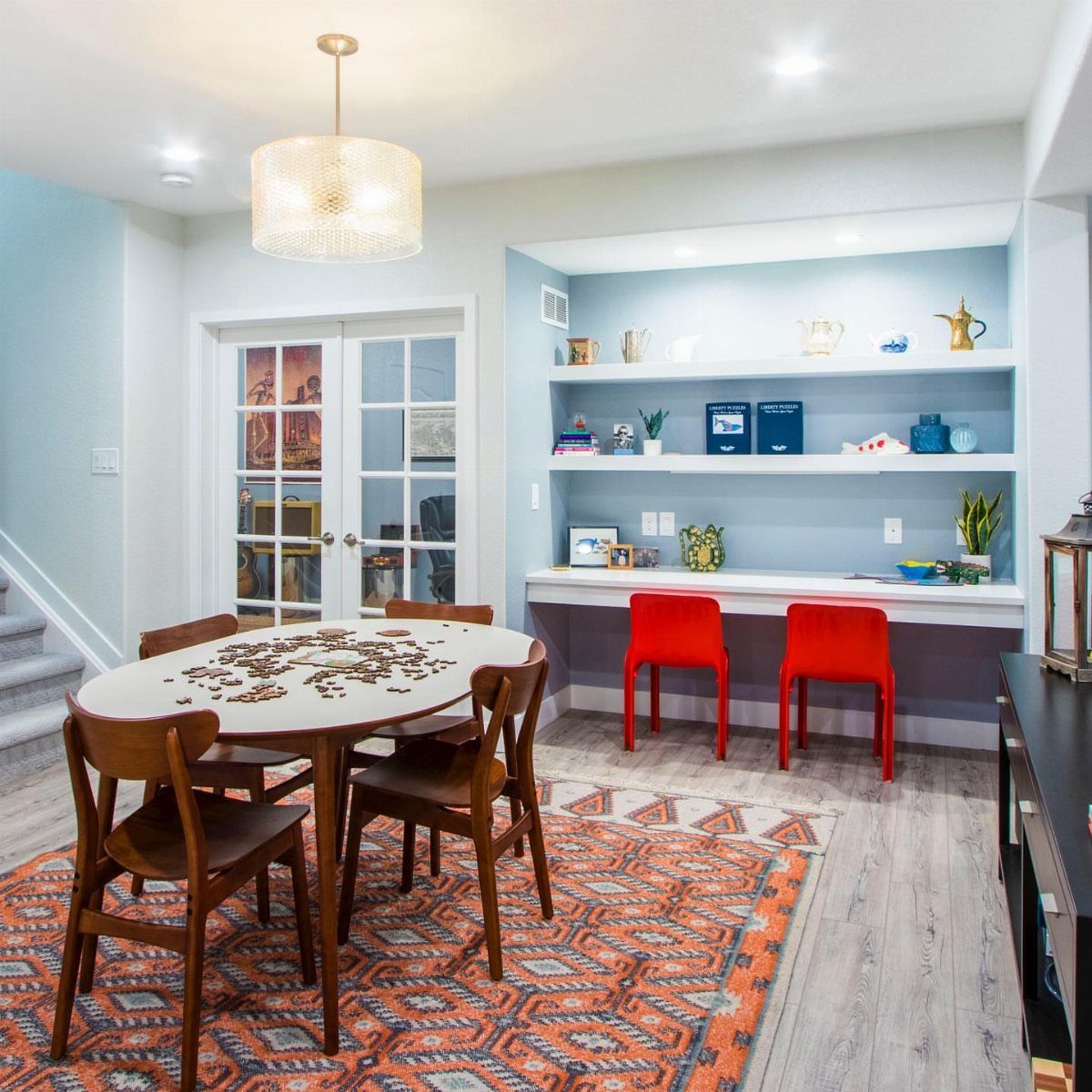 Built-in white desk with red chairs and shelving in a light blue room.