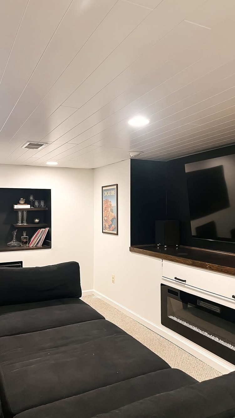 White planked drop ceiling with recessed lights in a finished basement living room