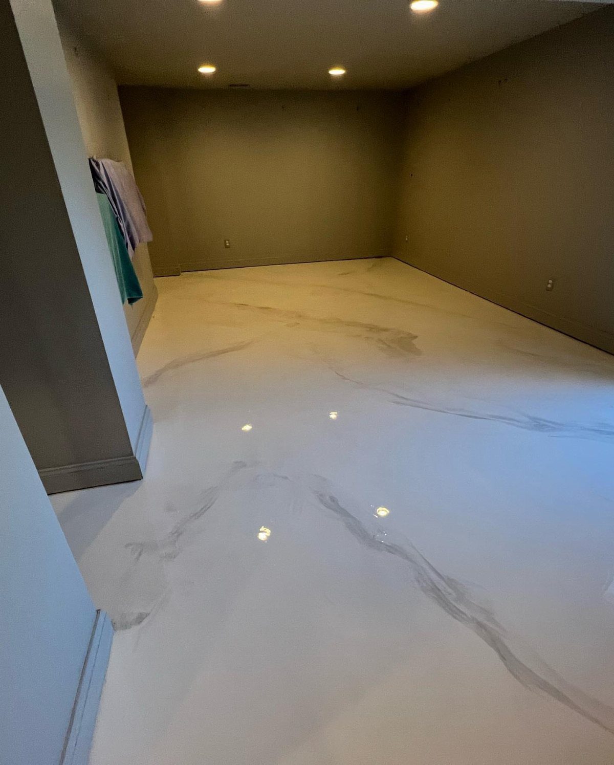 Glossy white basement floor with grey marble veining in an empty room