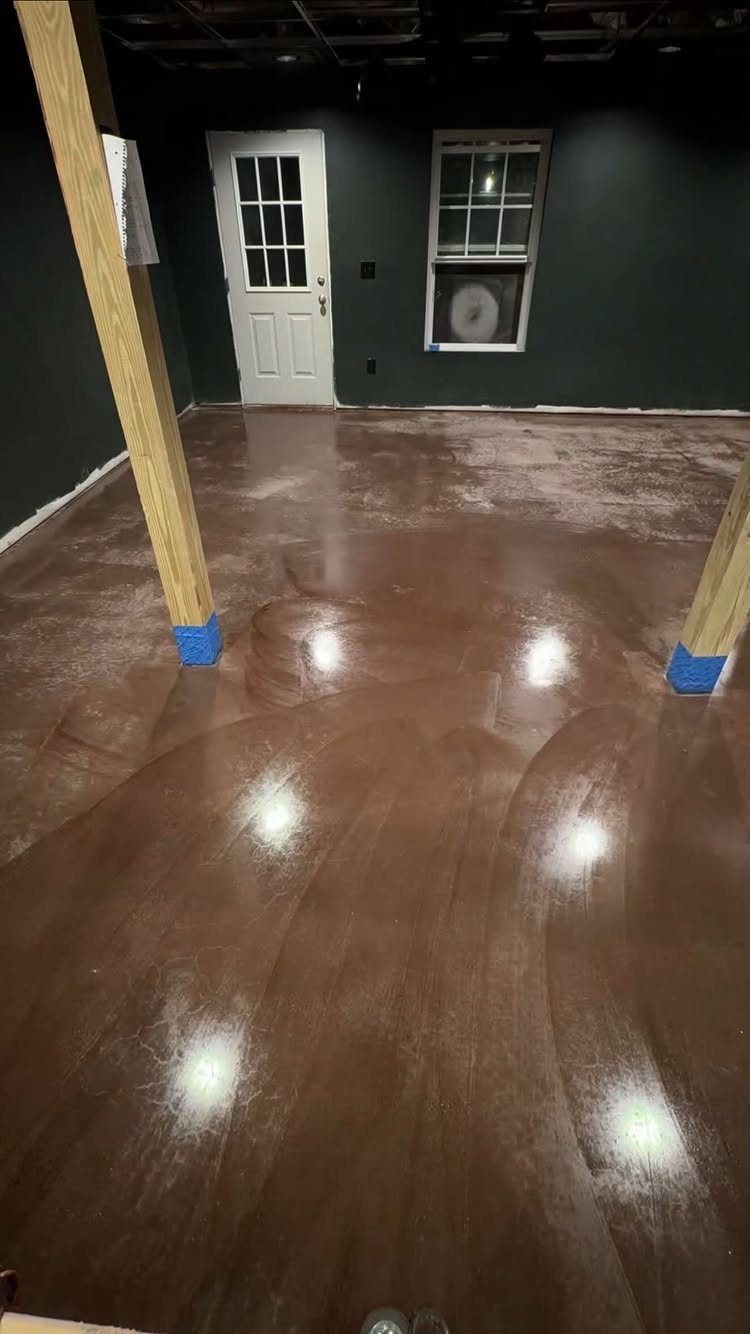 Glossy brown painted concrete basement floor with dark walls and wooden support beams.