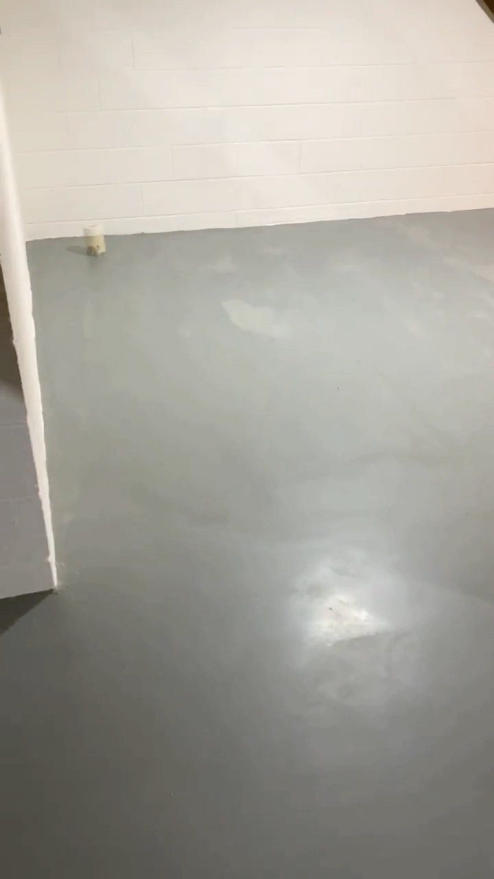 Light gray painted concrete floor against white paneled walls in a basement room.