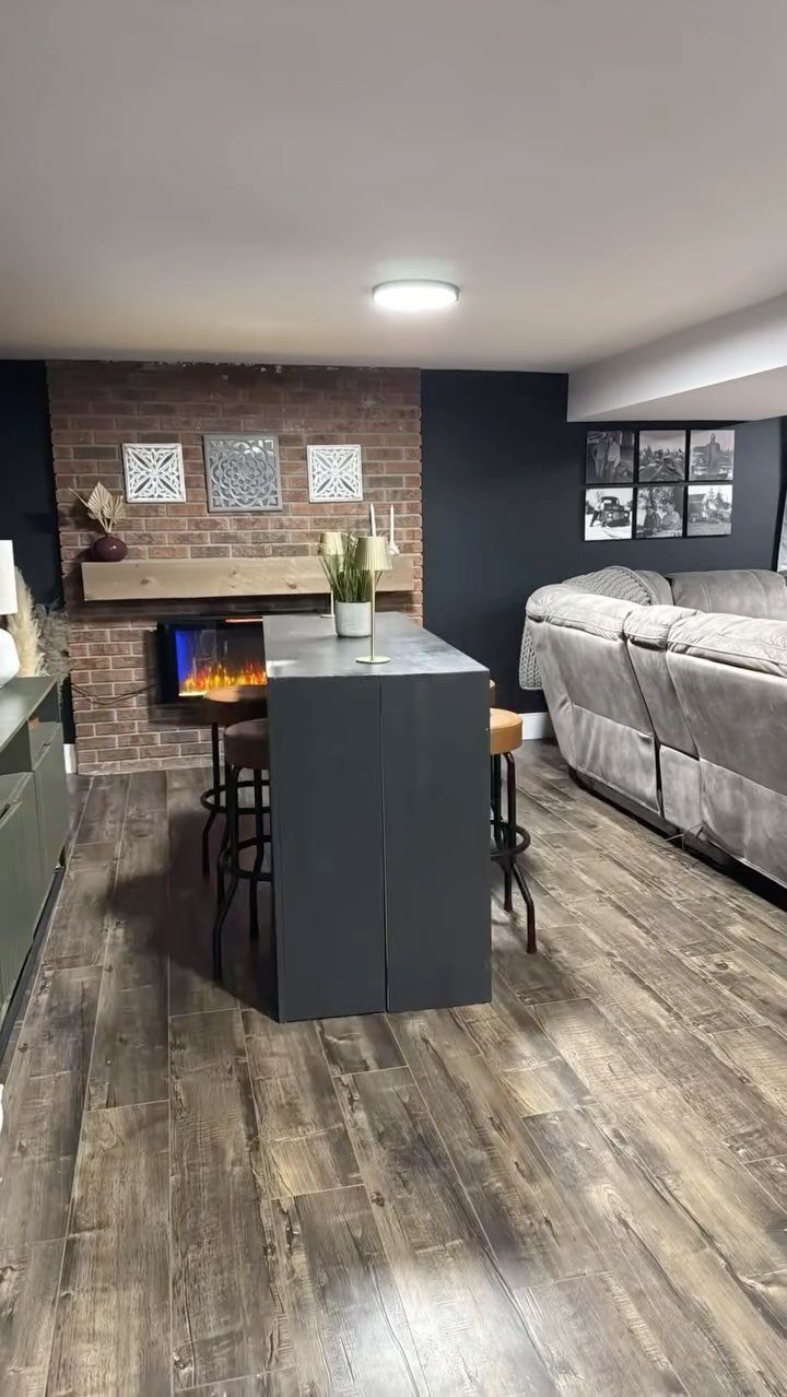Black bar stools tucked under a dark grey island in a finished basement.