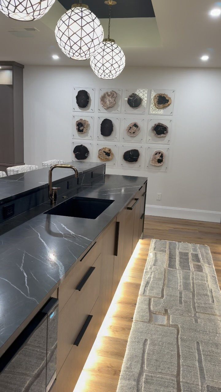 Modern basement bar featuring spherical pendant lights and warm under-cabinet LED strip lighting.