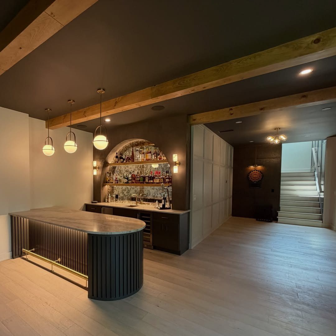 Curved peninsula bar with grey countertop and fluted dark wood in a basement
