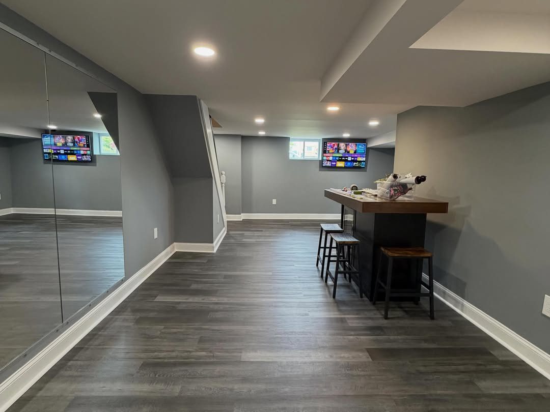 Finished basement man cave with a bar, stools, and wall-mounted television.