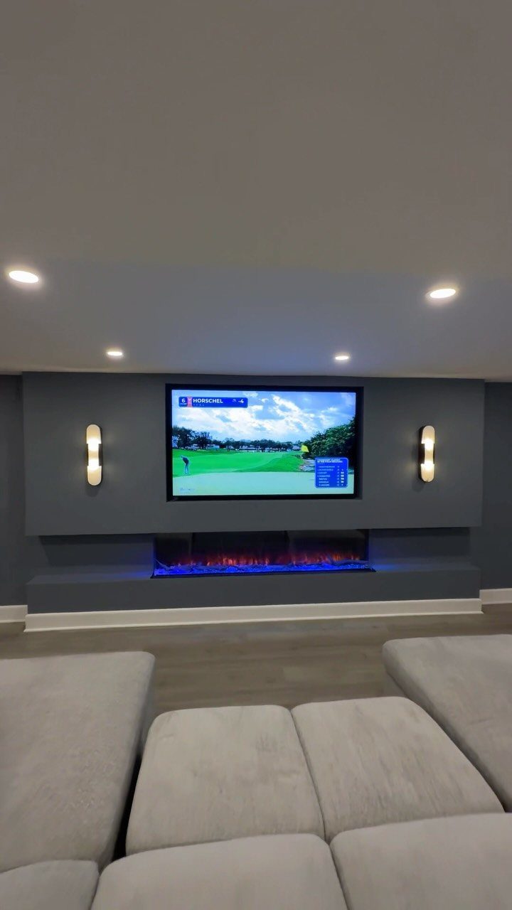 Modern basement man cave with grey walls, electric fireplace, and large sectional sofa.