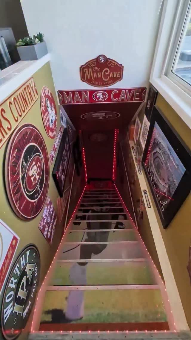 Staircase leading to a man cave decorated with sports memorabilia and red LED lights.