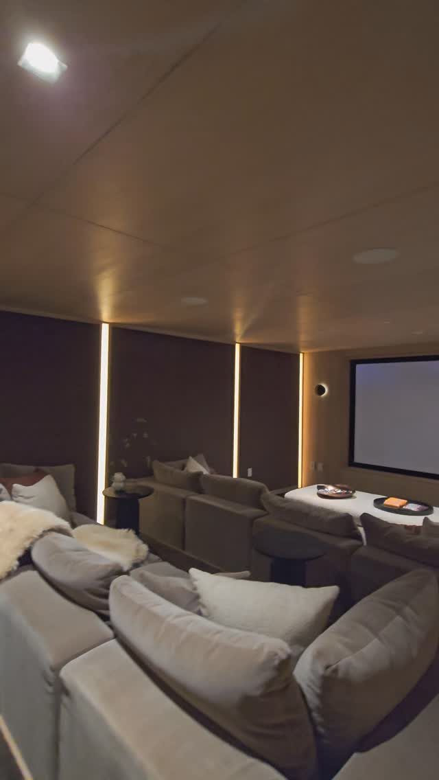 Home cinema room with grey reclining sofas and a large projection screen.