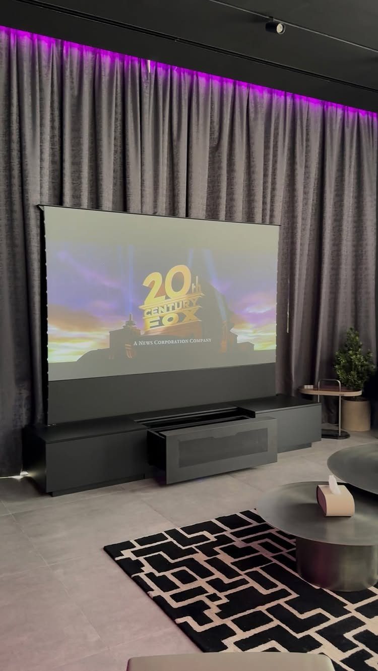 Large projection screen in a home theater with grey blackout curtains and purple lighting.