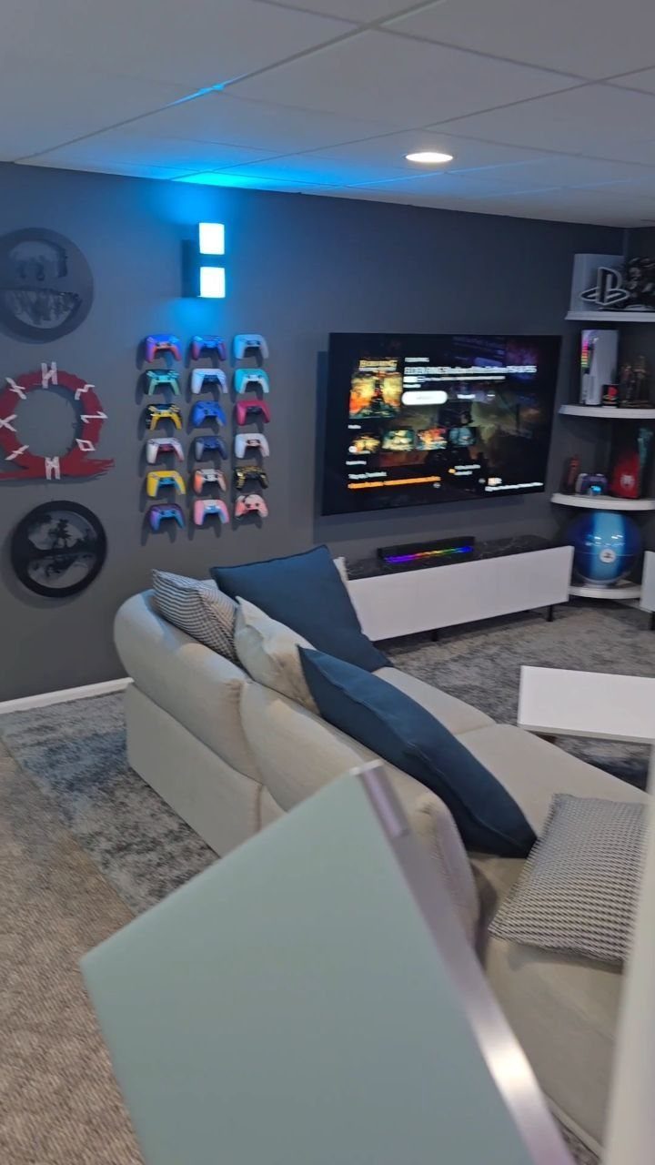 Gaming zone with a large TV, sectional sofa, and wall-mounted game controllers.