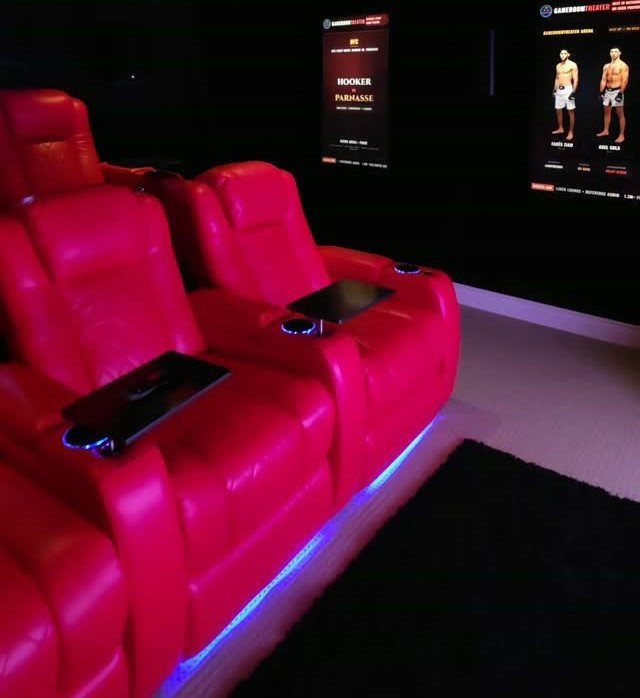 Red leather reclining theater seats with blue LED lighting in a dark room