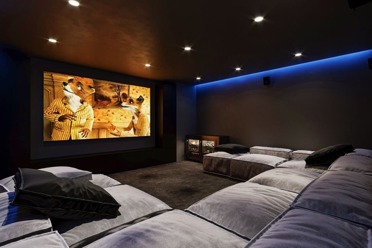 Low-profile grey modular seating in a dark home theater with a projection screen.