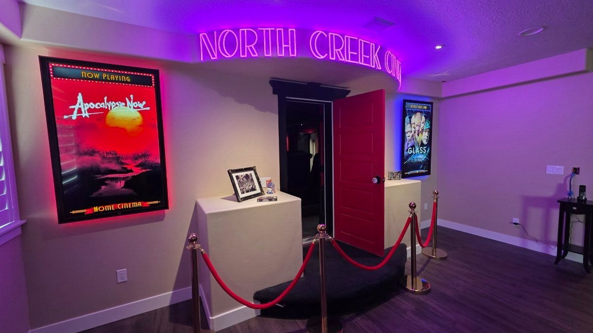 Home cinema entrance with purple neon signage, red velvet ropes, and movie posters.