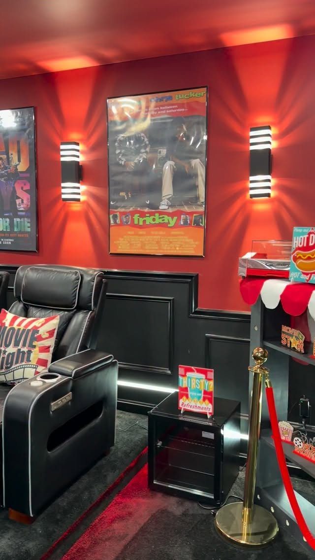 Home cinema room with red walls, movie posters, and a red velvet rope.