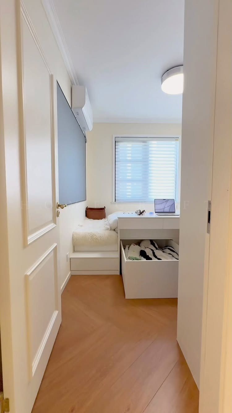 Small white bedroom featuring a platform bed and a desk with a laptop.