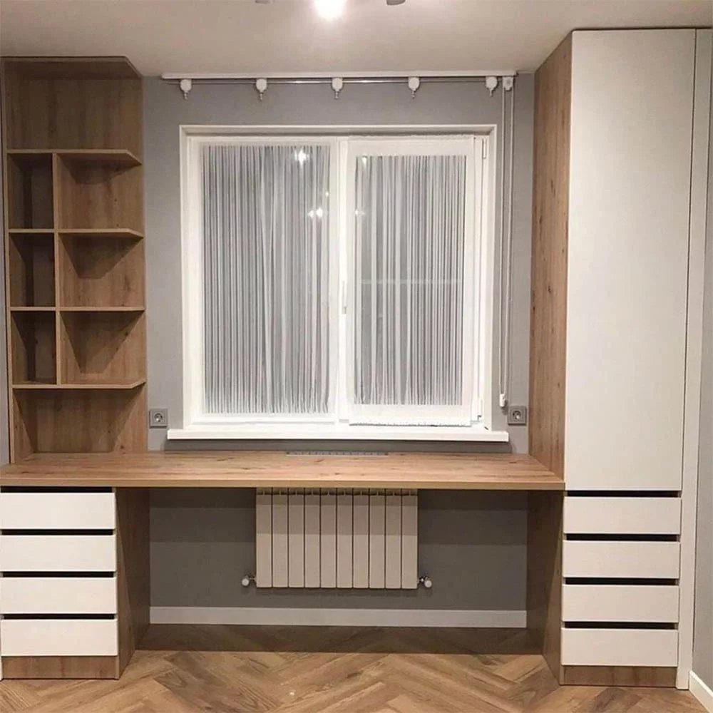 Light wood desk positioned under a window with flanking storage cabinets and shelves.