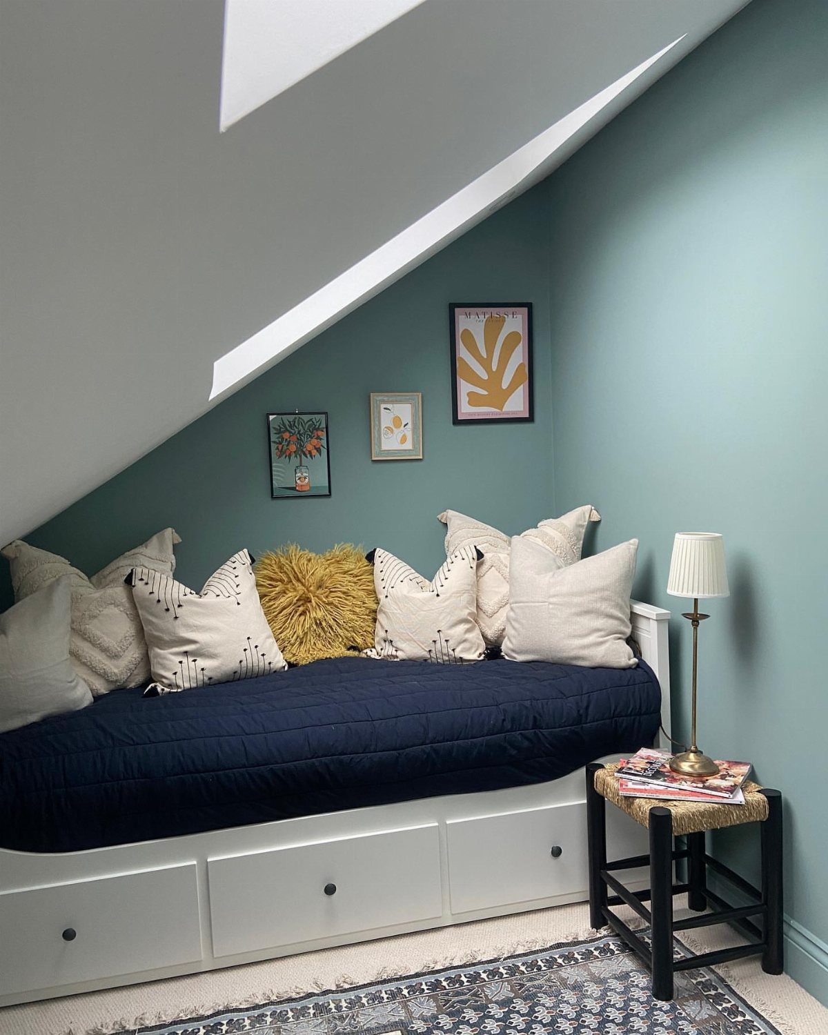 Light blue attic bedroom with a navy daybed and white built-in storage drawers.