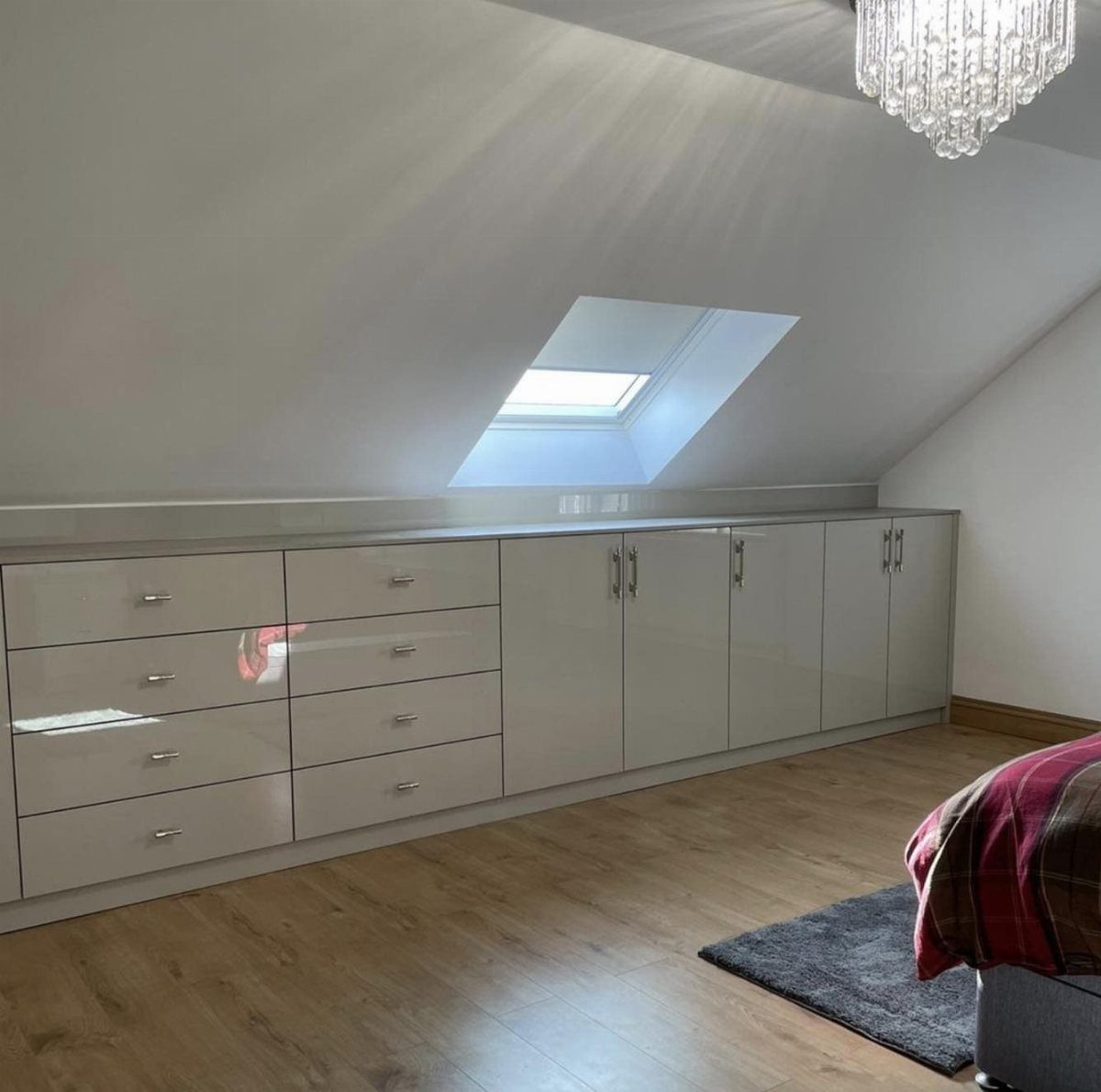 Low-profile white glossy cabinets under a sloped ceiling with a skylight in attic.