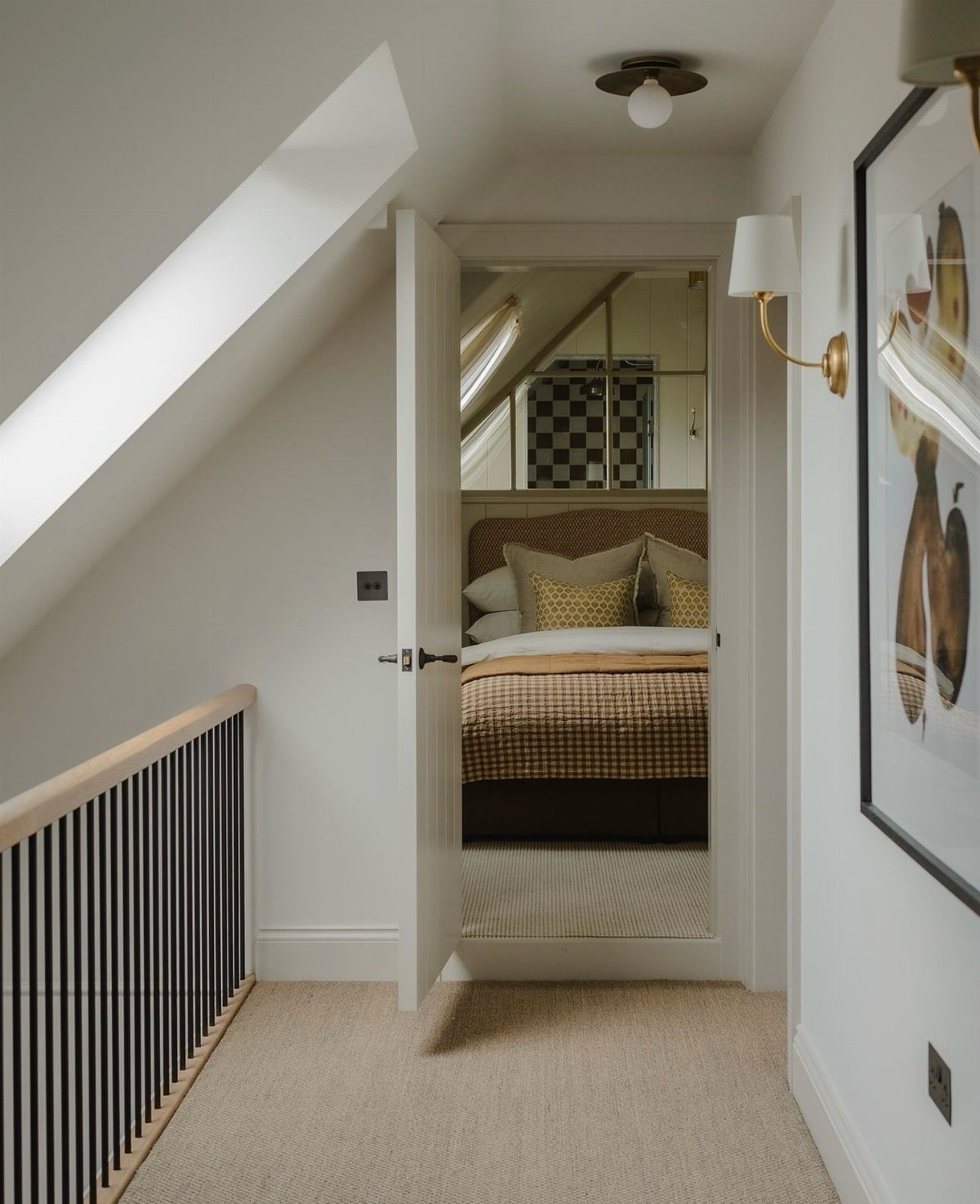 Attic bedroom with sloped ceilings seen through an open white door from a hallway.