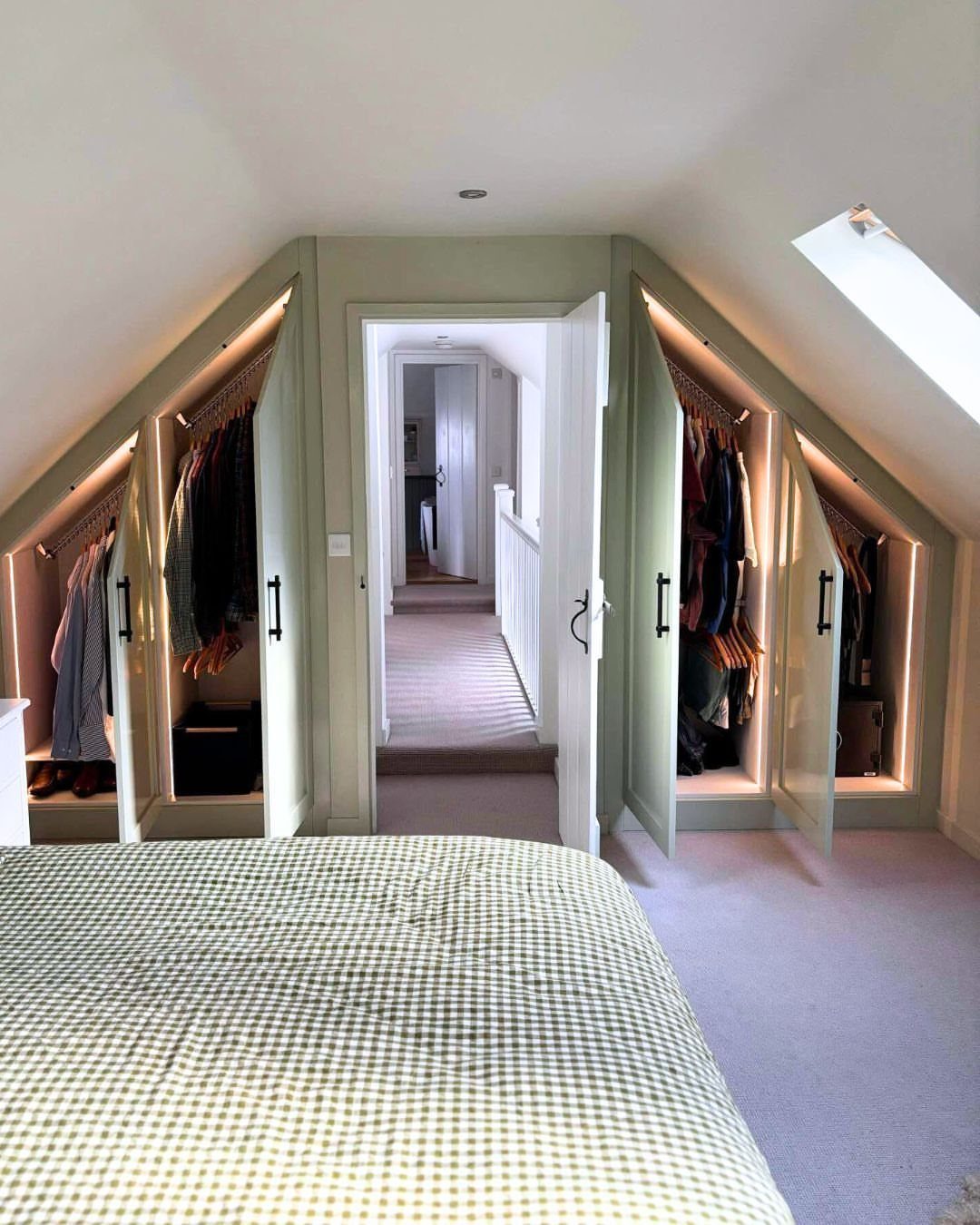 Attic bedroom with light green sloped ceilings and walls and built-in wardrobes.