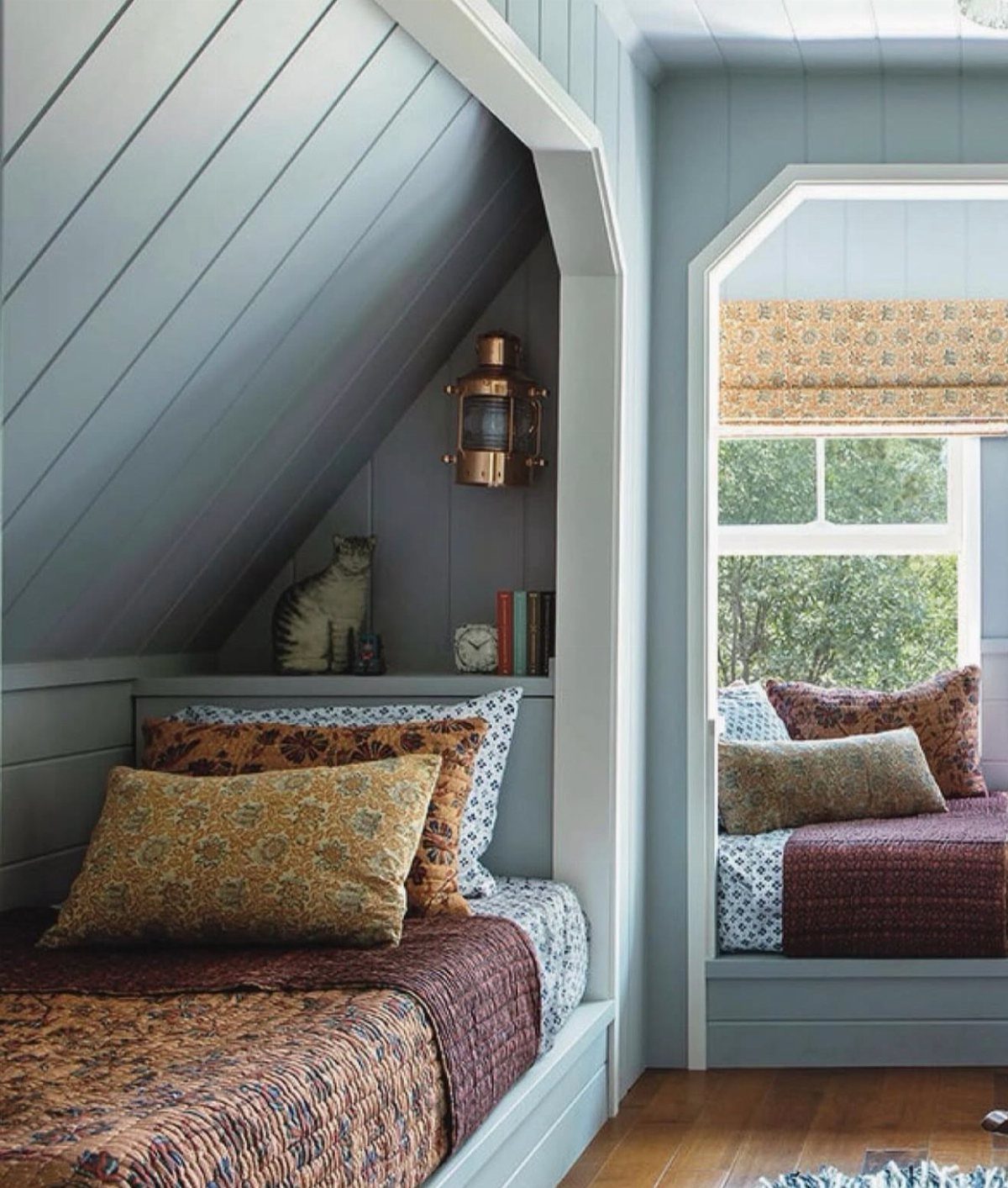 Light blue attic bedroom with vertical shiplap paneling and a cozy window seat.
