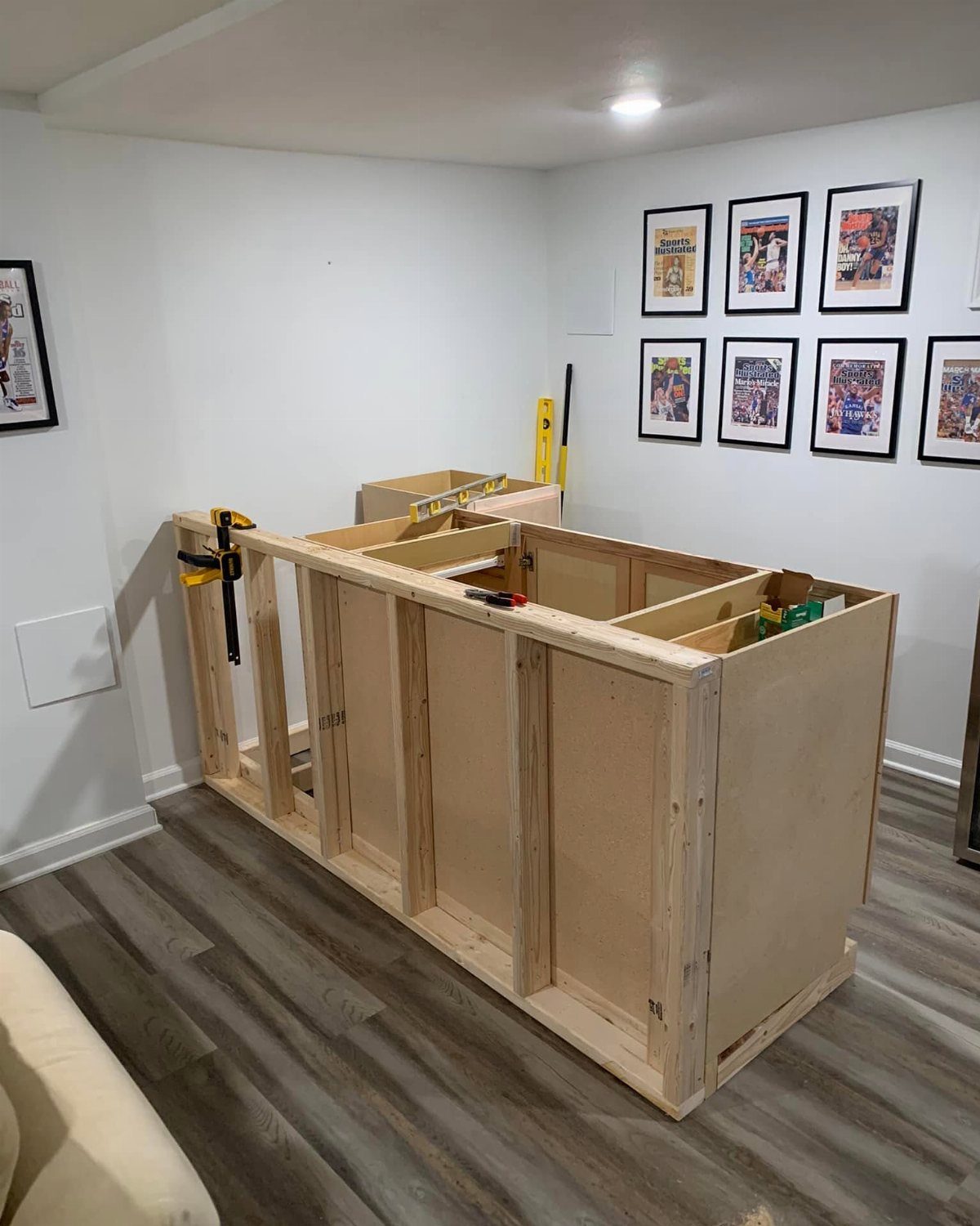Unfinished wooden bar frame made of plywood in a white room with flooring.