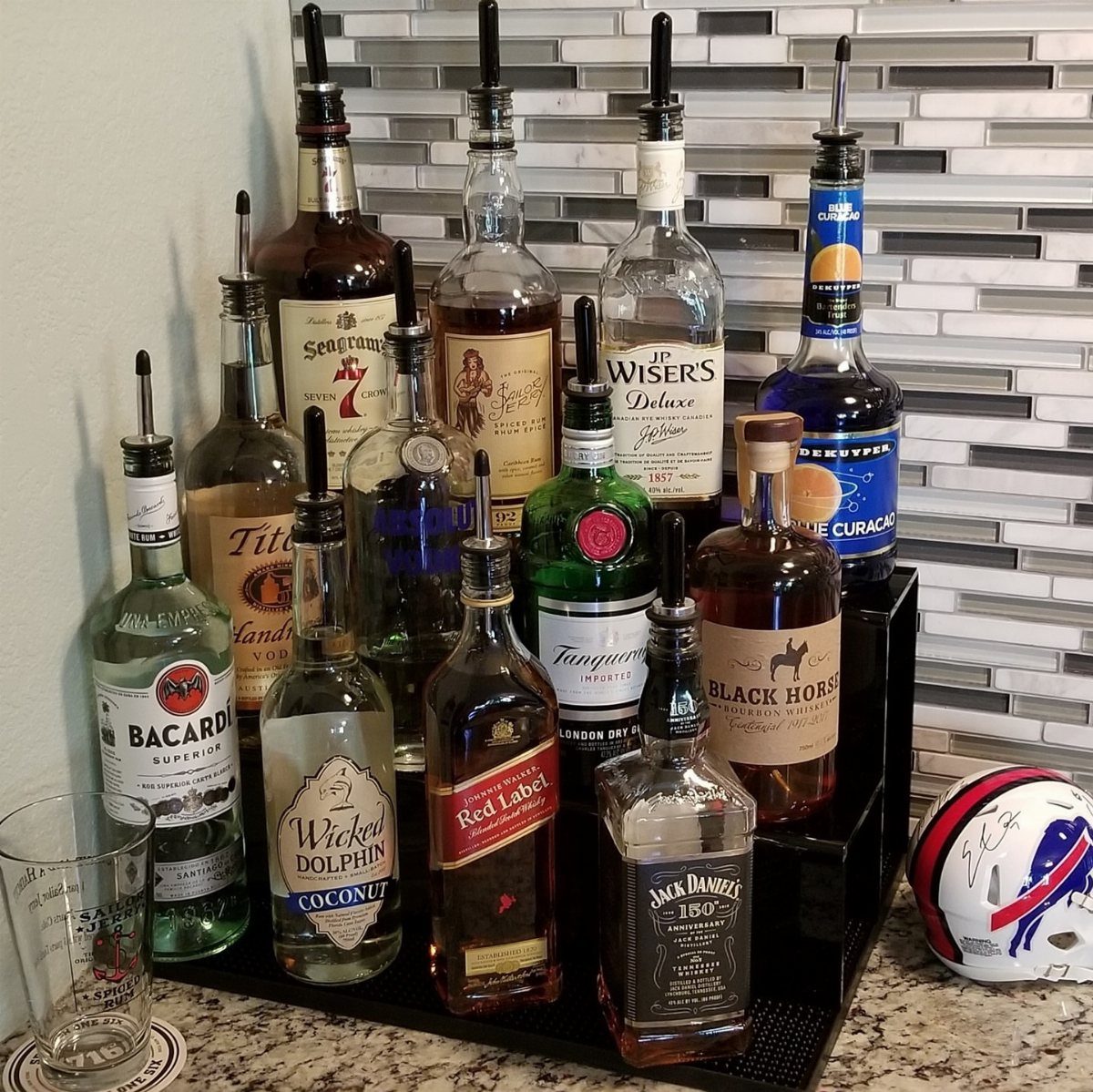 Assorted liquor bottles with pour spouts on a black organizer on a countertop