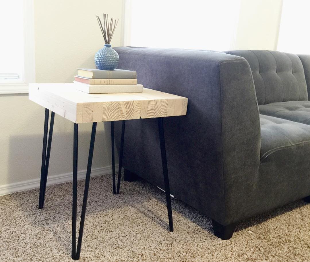 Butcher block table with black hairpin legs next to a grey tufted sofa.