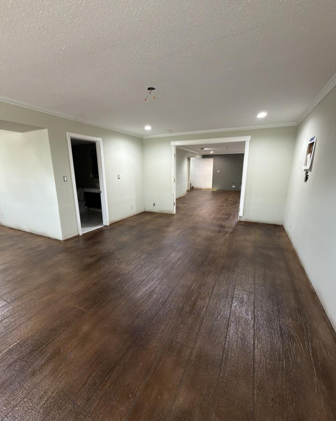 Empty room with brown wood flooring and a white textured drywall ceiling.