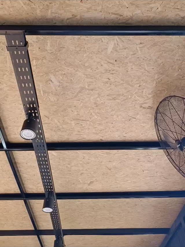 OSB wood ceiling panels with black metal support beams and spotlights