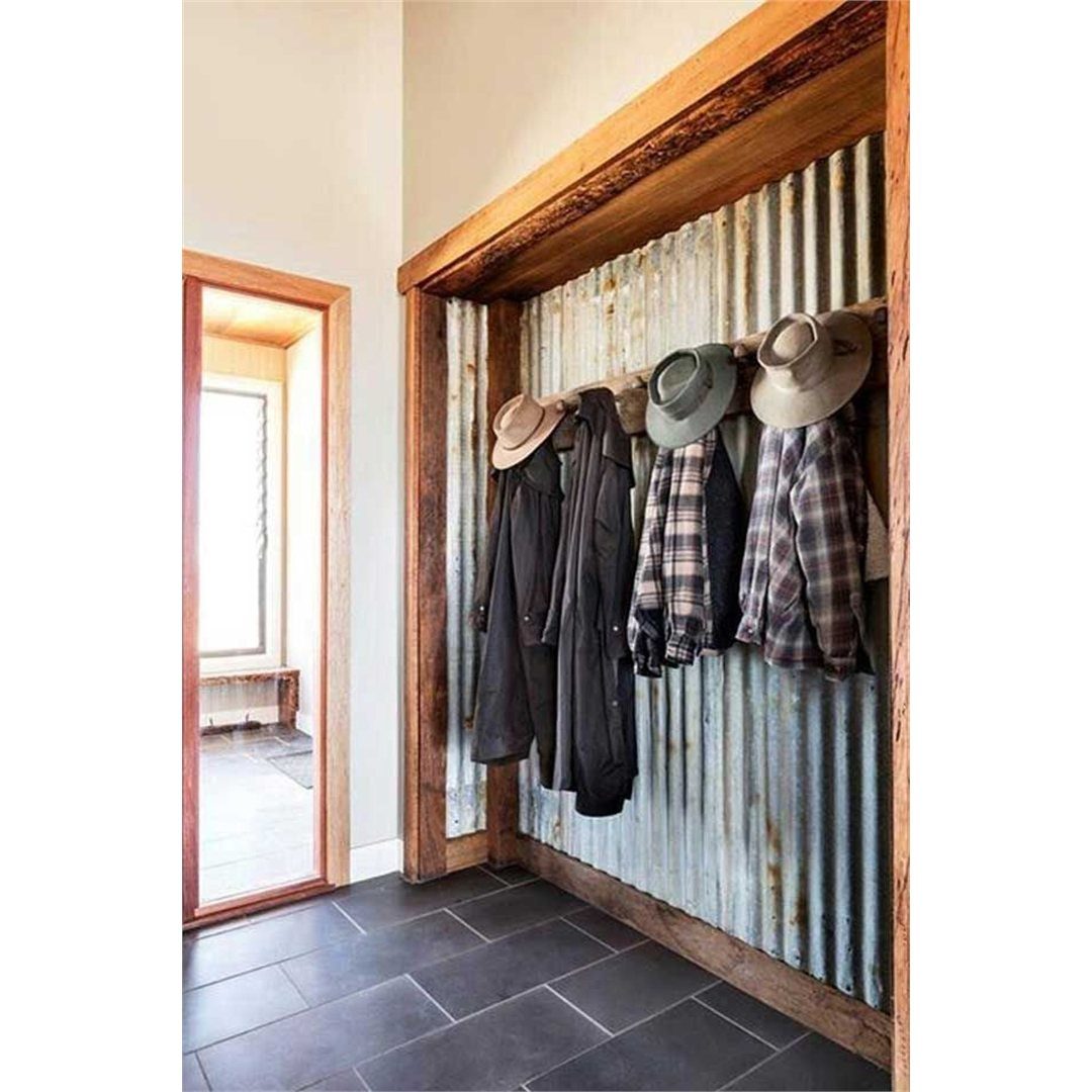 Corrugated metal wall in a mudroom with hanging jackets and rustic wood framing.