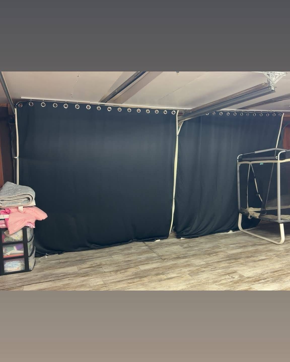 Black grommet curtains covering a wall in a room with light wood flooring.