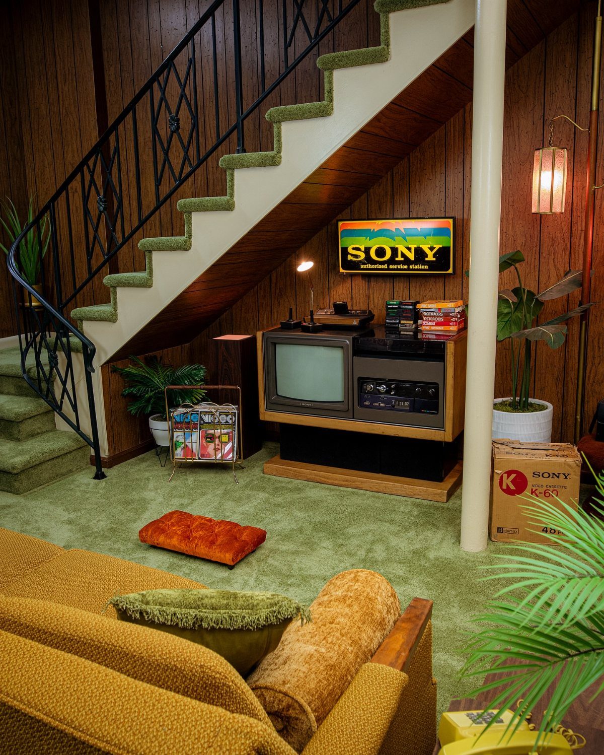 Retro basement with brown wood-paneled walls, green carpet, and vintage television set.