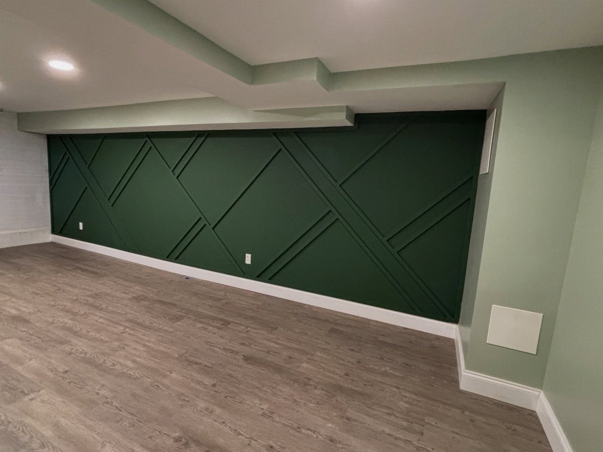 Dark green accent wall with geometric raised slats in a modern basement room