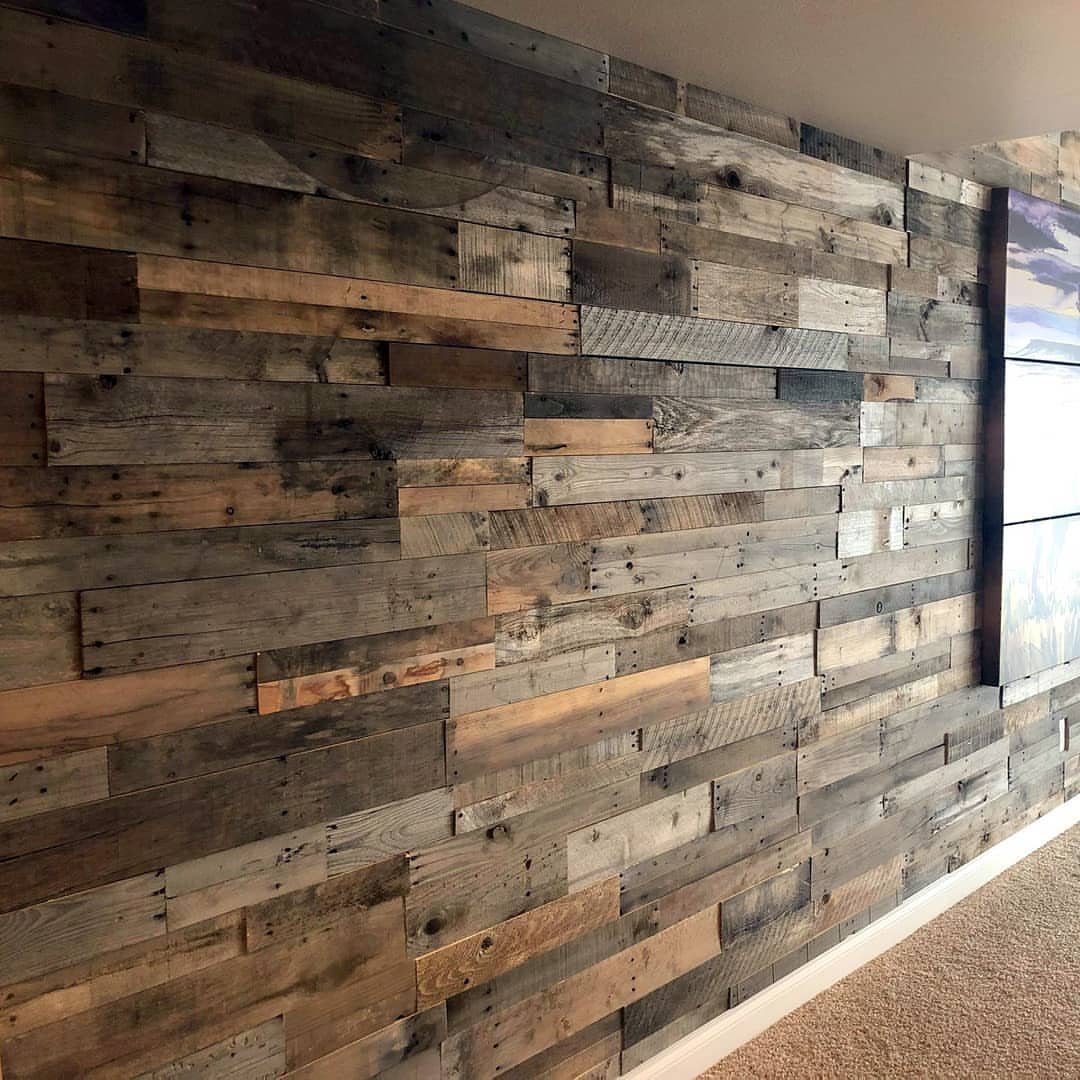 Reclaimed wooden planks in grey and brown tones covering a rustic interior wall.