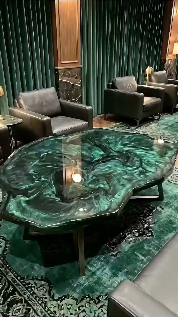 Emerald green swirling resin coffee table surrounded by grey leather chairs and green curtains.