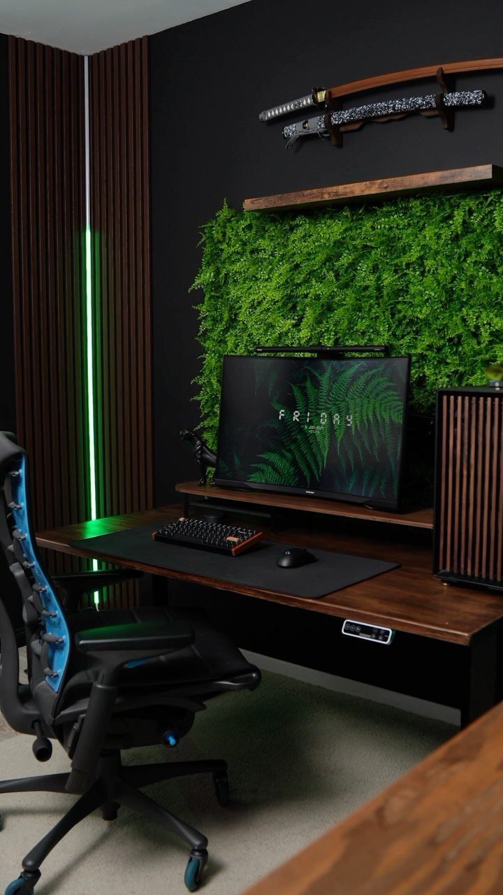 Gaming office setup with a green moss wall, wooden desk, and black chair.