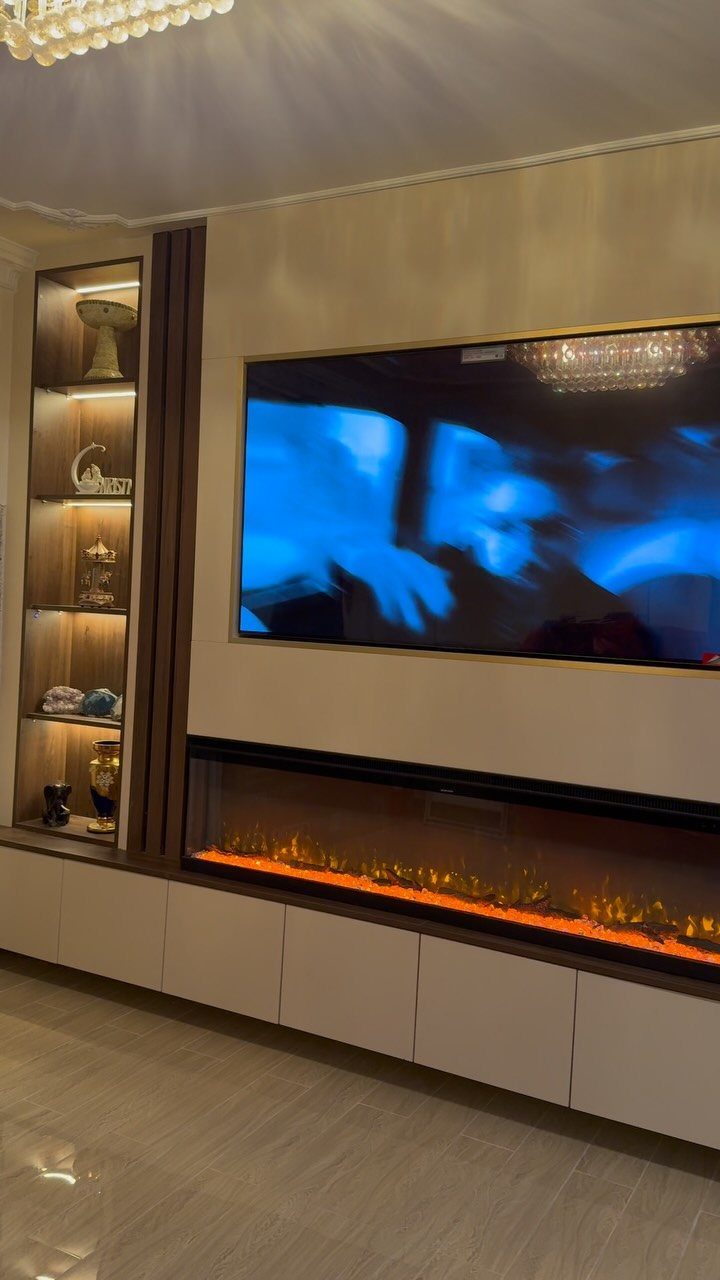 Modern entertainment wall with a mounted TV, electric fireplace, and built-in shelving.