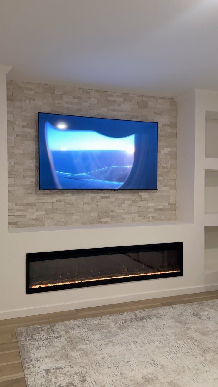 Modern entertainment wall with a linear fireplace and mounted television on stone tile.