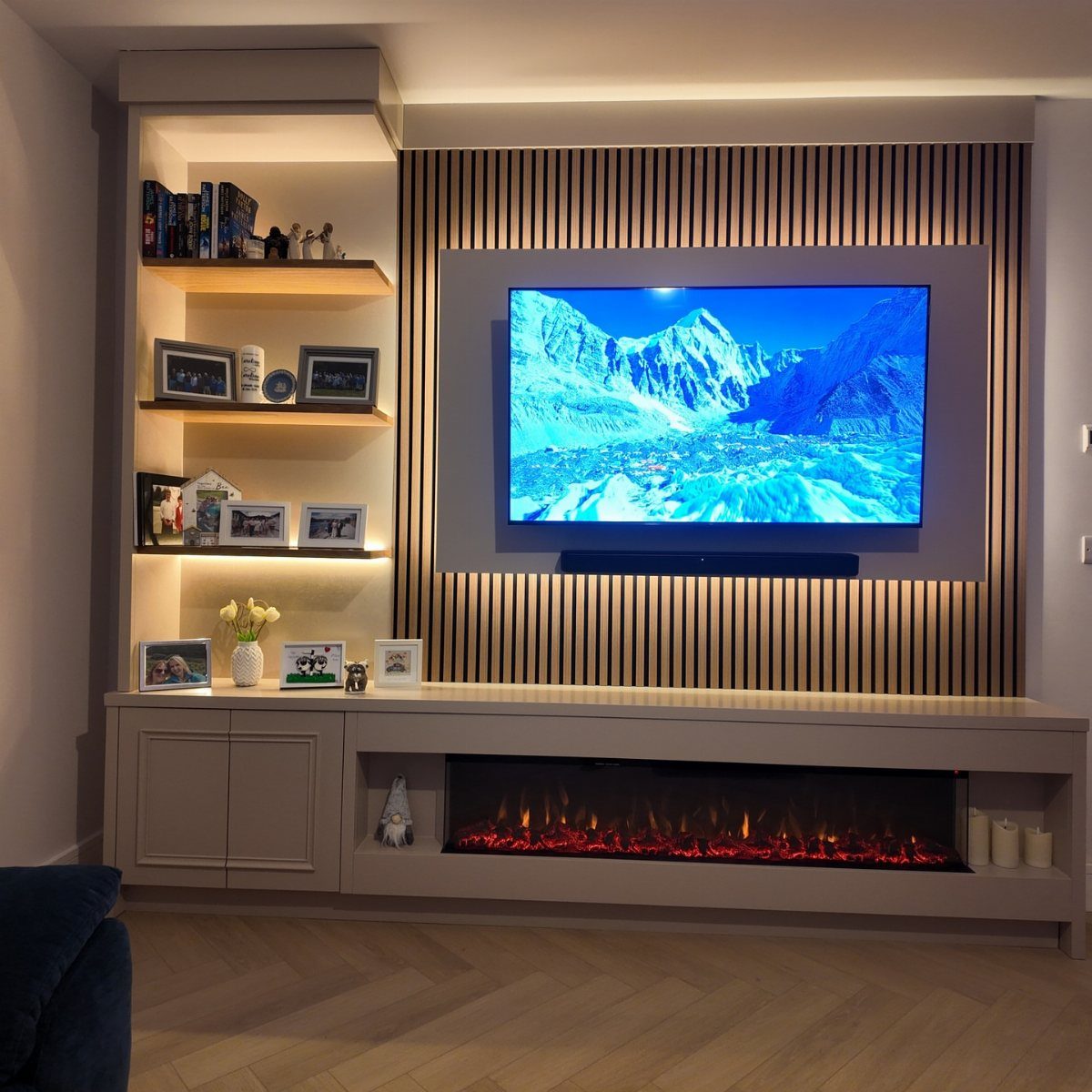 TV mounted on a slatted wood wall above a linear electric fireplace