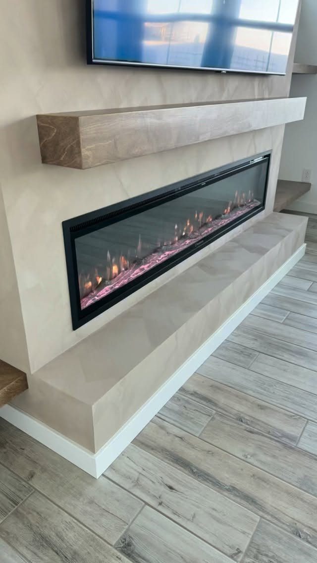Modern entertainment wall with a linear electric fireplace, wood mantel, and mounted television.